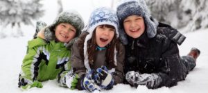 Kids laying in snow smiling