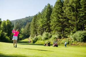 Woman driving off fairway while golf group waits