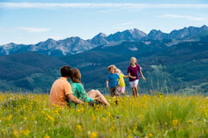 Family sitting in field in front of mountain range