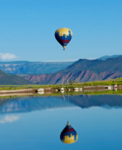Hot air balloon flying over lake