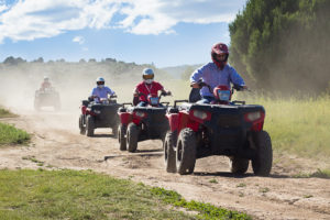 Group riding four wheelers down dirt path