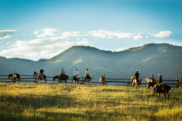 People horseback riding in front of mountains