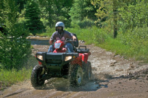 Man riding four wheeler through dirt and mud