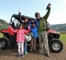 Family smiling and waving in front of ATV