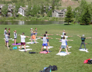 People doing yoga by a lake outside