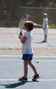 Child on tennis court with a racquet