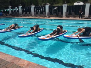 People doing yoga in pool on paddle boards