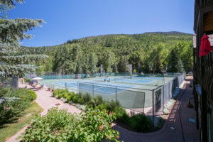 Clay tennis courts by trees and mountain