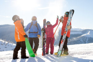 Family on top of slope holding skis and snowboard